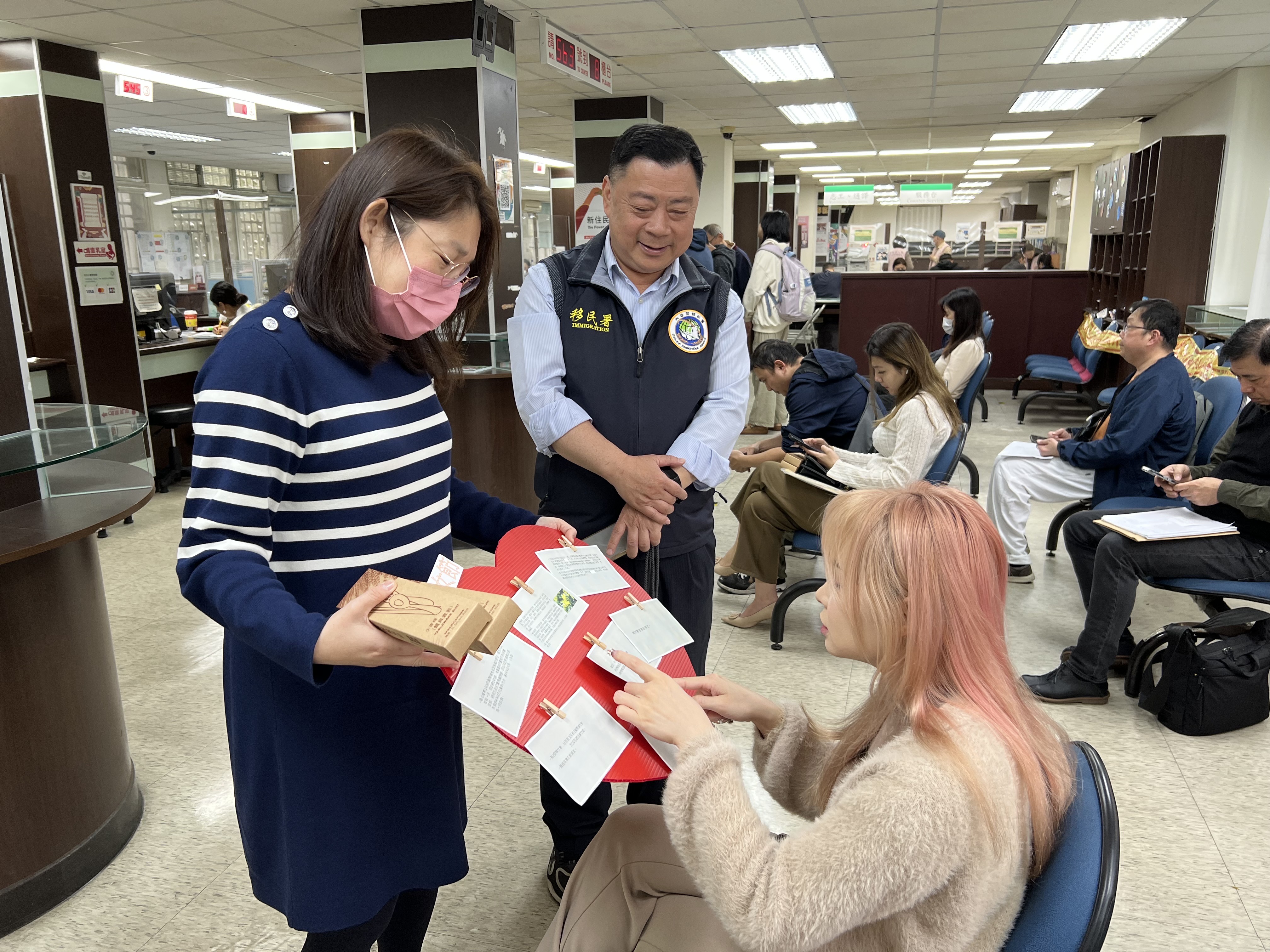 圖一、新北市服務站主任林財榮(中間)與社工王文琍(左一)向民眾介紹「花語傳情婦女節」活動